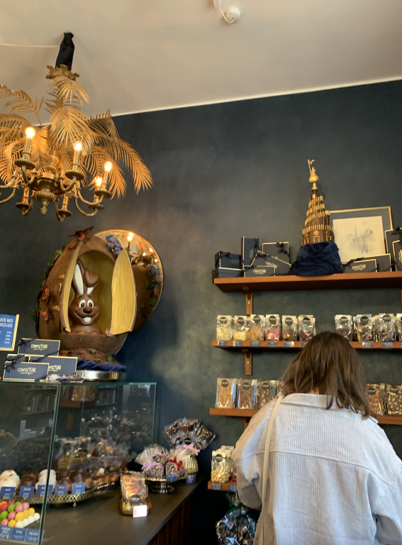 A woman shops in a chocolate shop next to a giant chocolate rabbit.